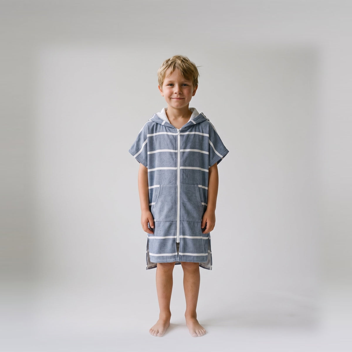 Amalfi kids hooded towel in navy and white stripes worn by a young boy, studio photo, front view