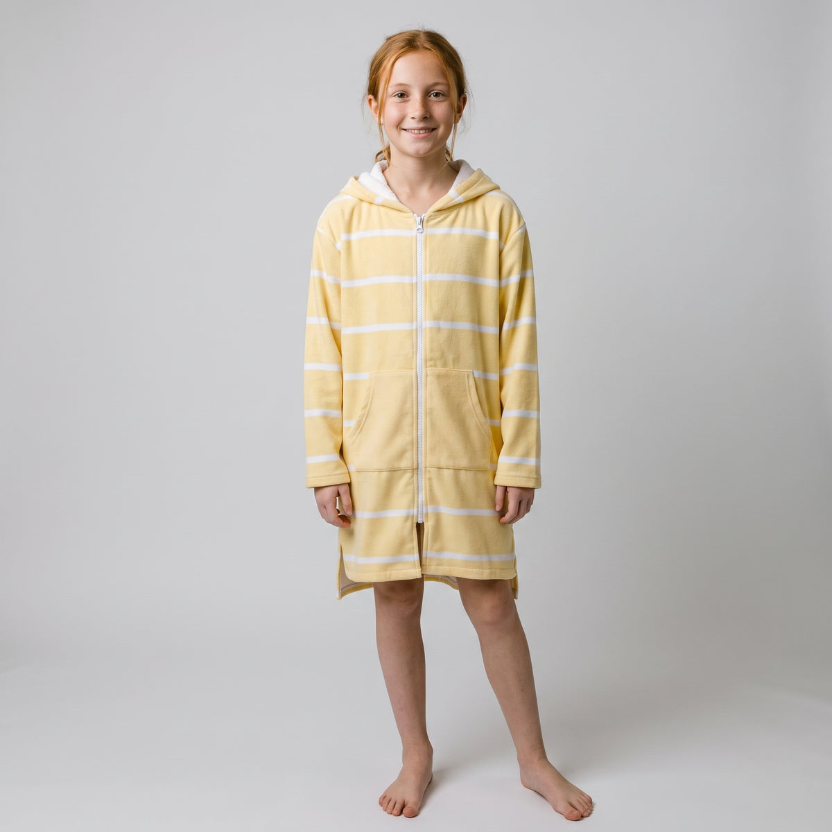 Girl in the long sleeve Amalfi yellow and white striped kids hooded towel, studio front view