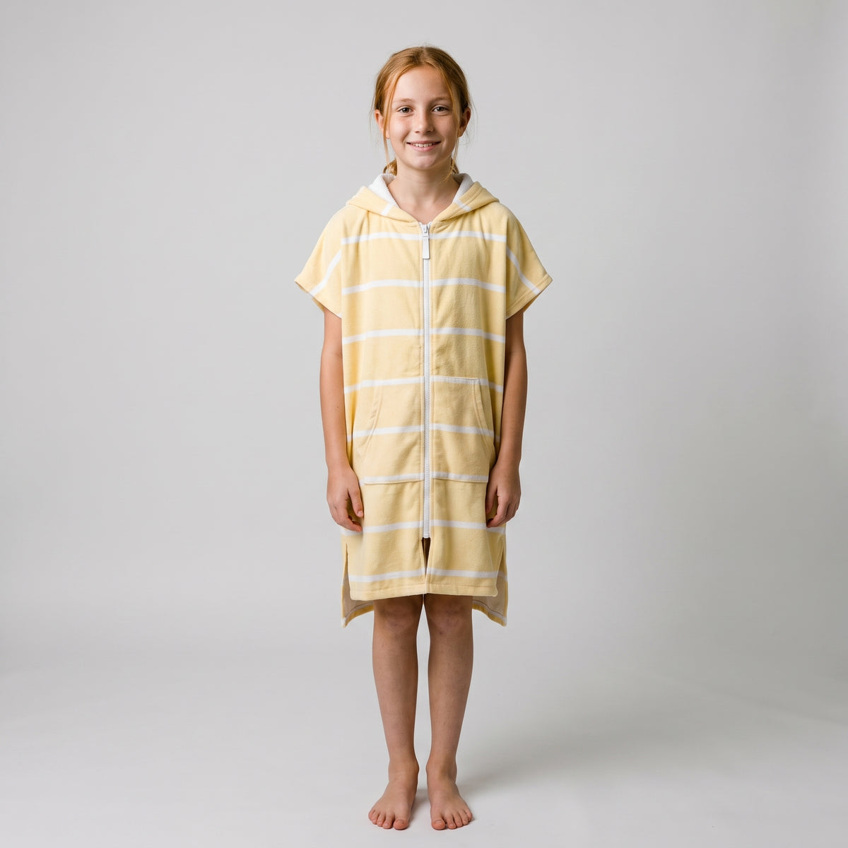 Amalfi kids hooded towel in yellow and white stripes worn by a girl, studio photo, front view
