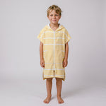 Young boy wearing Amalfi yellow and white striped kids hooded towel, studio photo, front view
