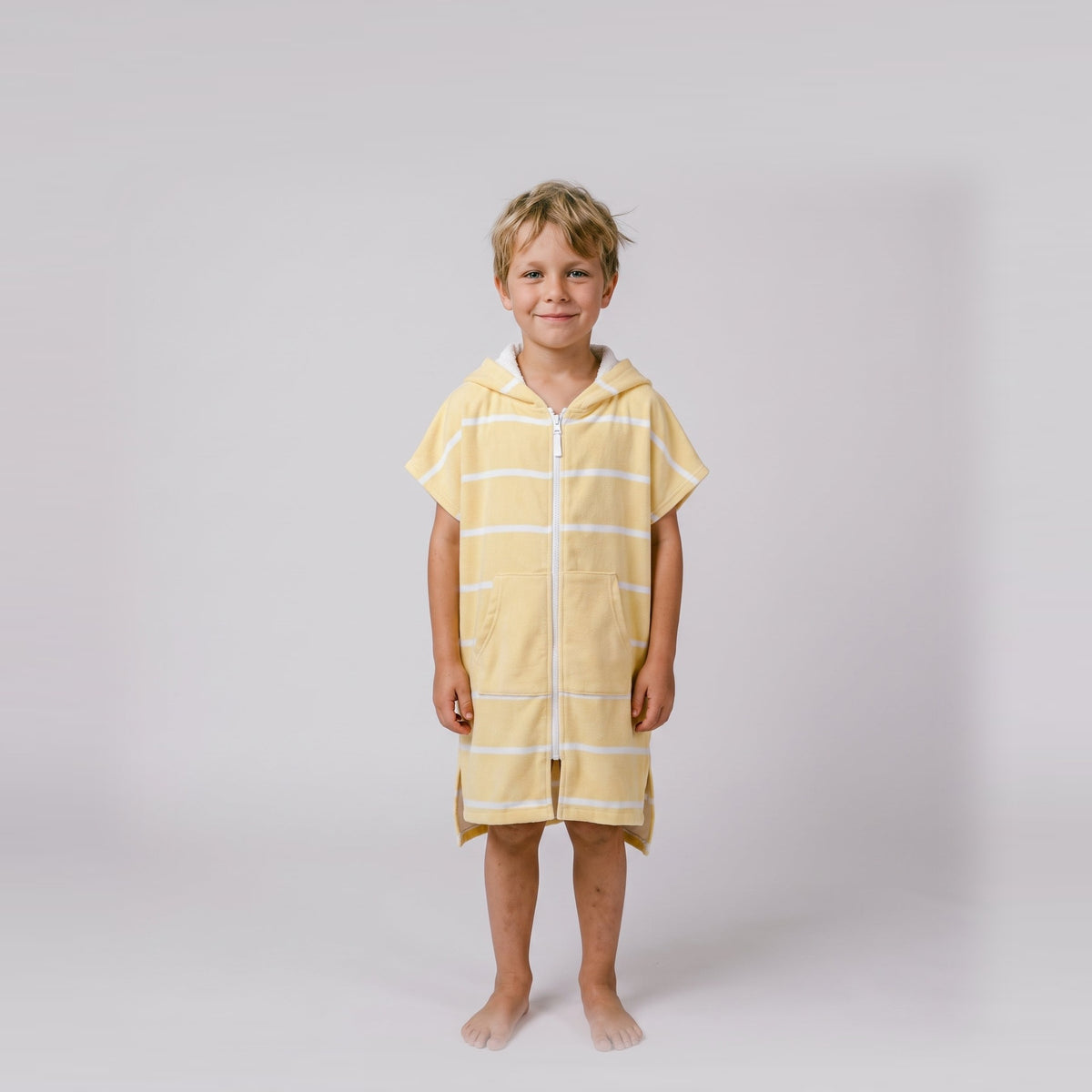 Young boy wearing Amalfi yellow and white striped kids hooded towel, studio photo, front view