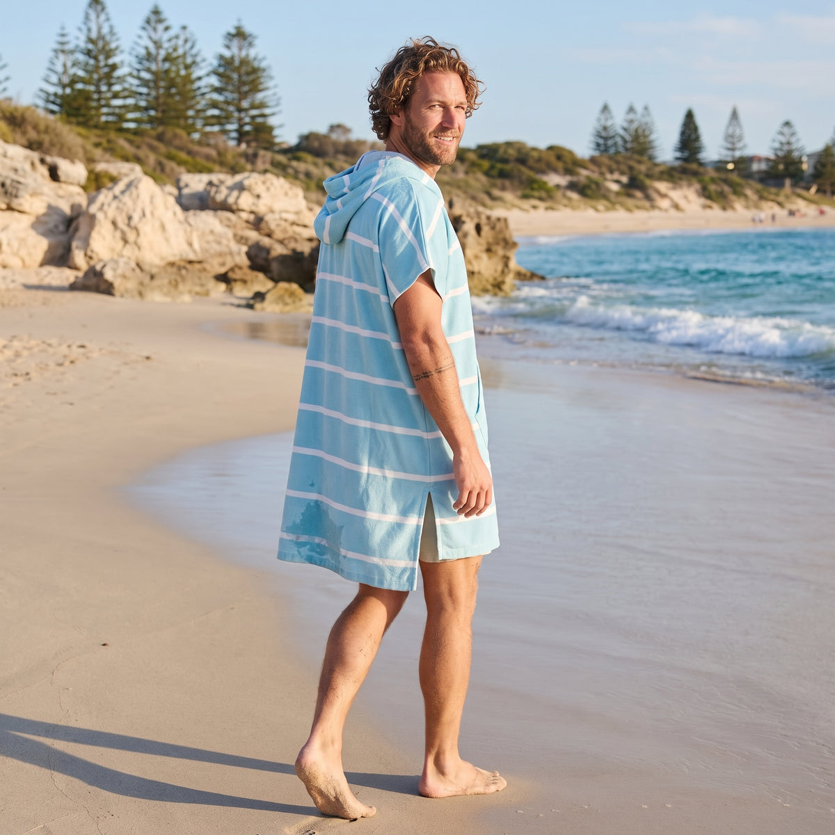 Man wearing the Amalfi Aqua White Turkish hooded towel while walking along a Western Australian beach