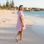 Woman wearing the Amalfi Pink White Turkish hooded towel while walking along a Western Australian beach