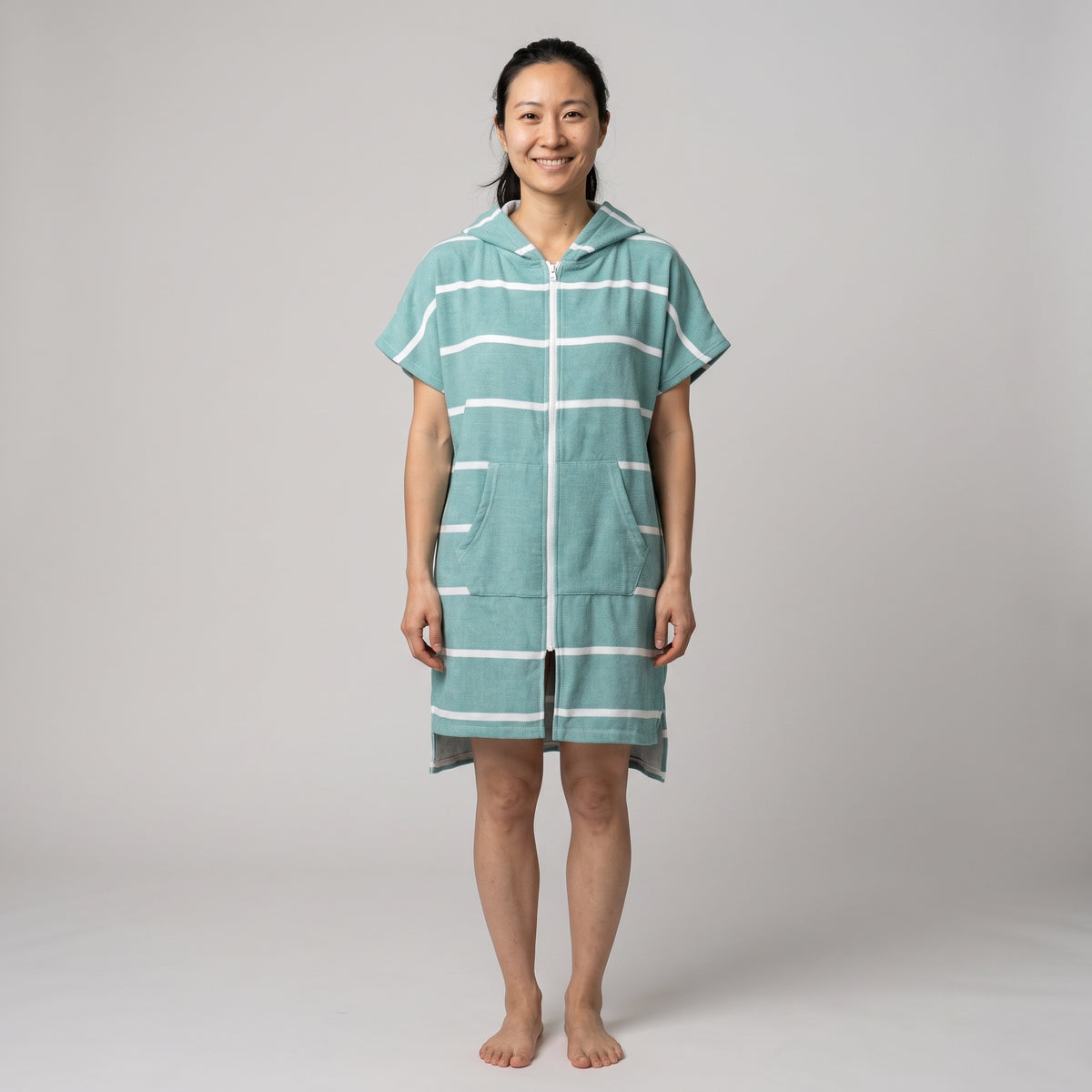 Woman wearing the Amalfi Teal White Turkish hooded towel, front view on a plain studio background
