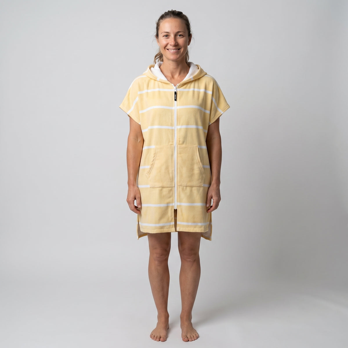 Woman wearing the Amalfi Yellow White Turkish hooded towel, front view on a plain studio background