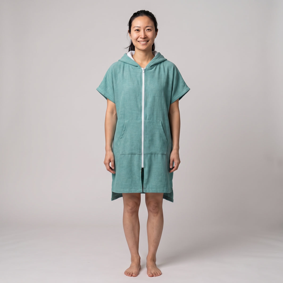 Woman wearing the Santorini Teal hooded towel, front view on a plain studio background