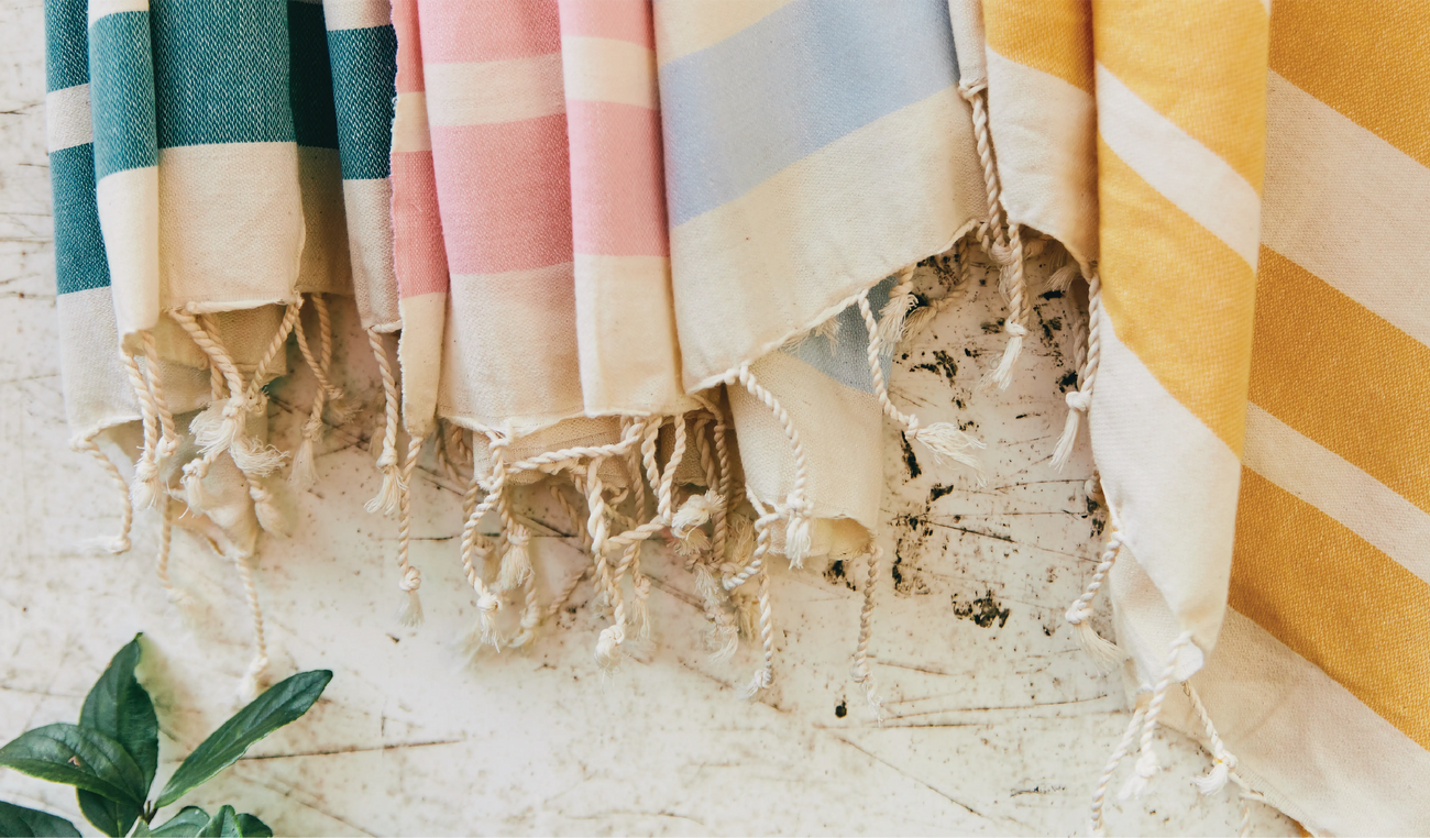 Moonessa Turkish towels in pastel stripes hanging in a row, showing their hand-twisted tassels