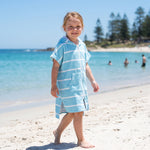 Amalfi kids hooded towel in aqua and white stripes worn by a young girl, on Cottesloe Beach, Perth