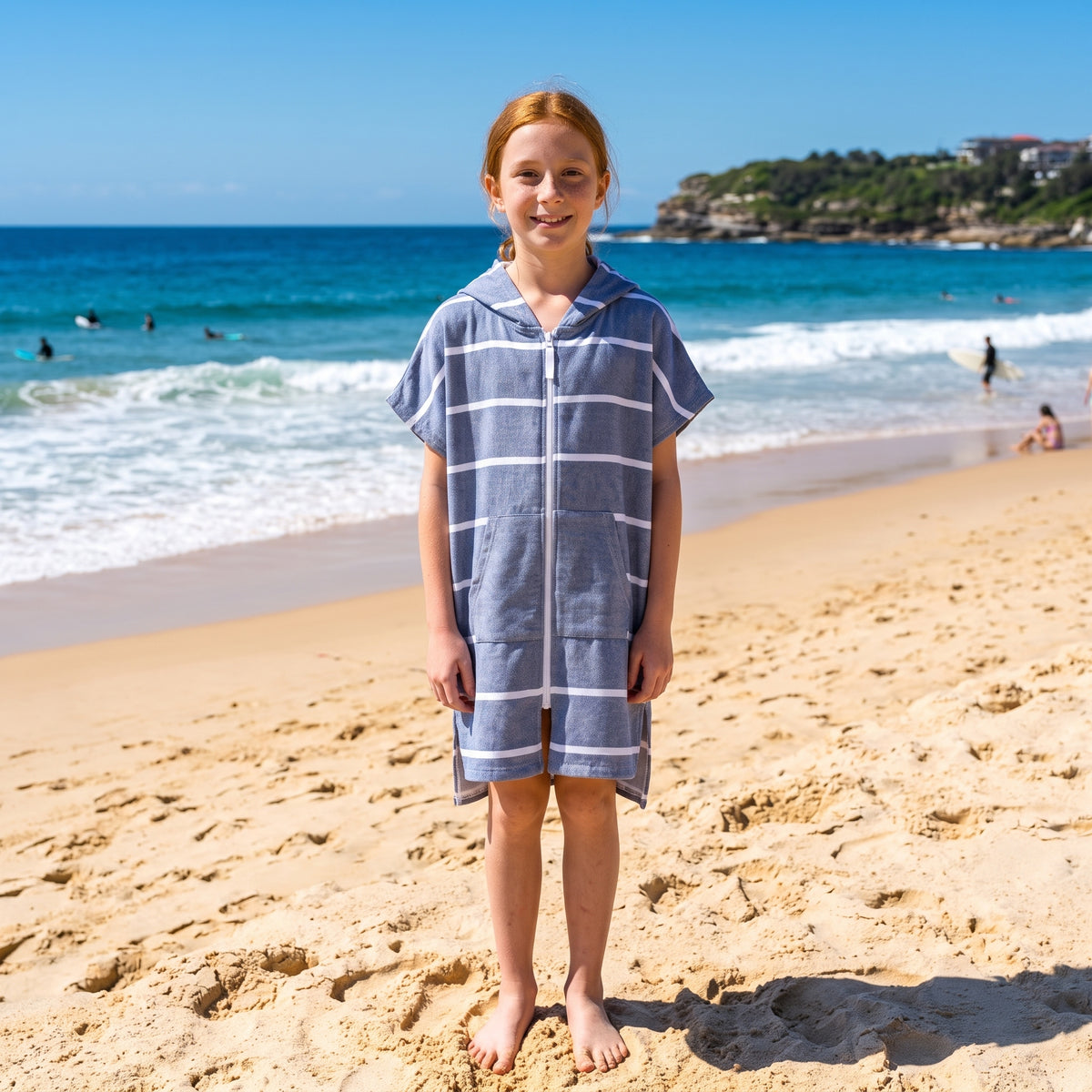 Girl wearing Amalfi navy and white striped kids hooded towel, on Bondi Beach, Sydney
