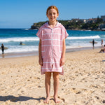 Girl wearing Amalfi pink and white striped kids hooded towel, on Bondi Beach, Sydney