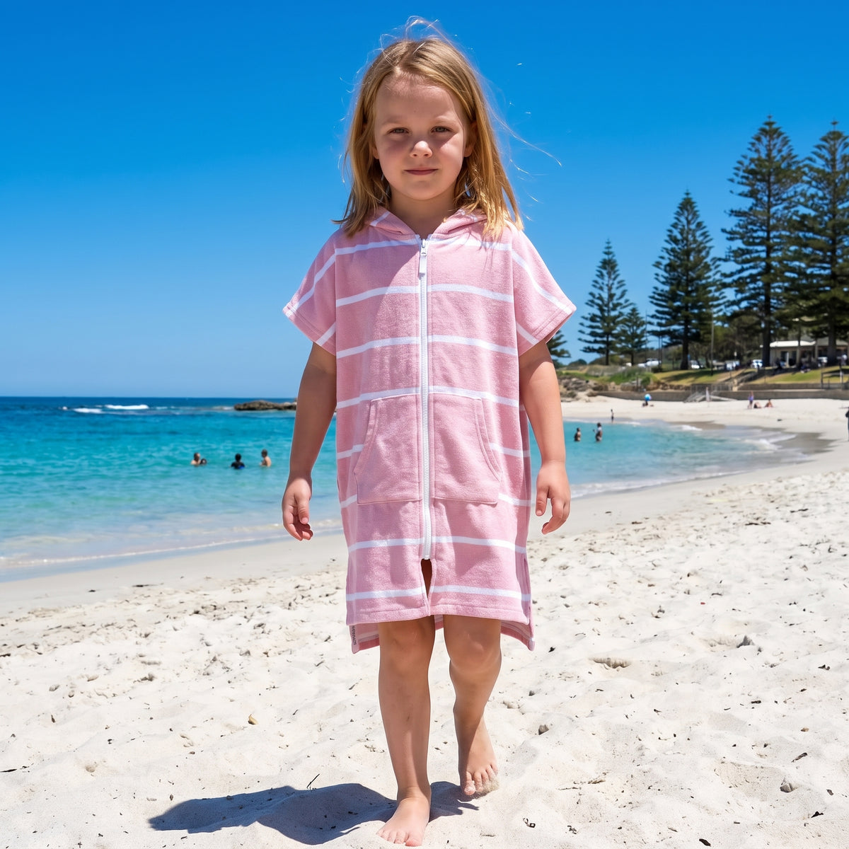 Young girl wearing Amalfi pink and white striped kids hooded towel, on Cottesloe Beach, Perth
