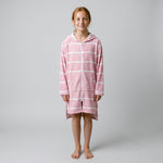 Long sleeve Amalfi kids hooded towel in pink and white stripes worn by a girl, studio front view