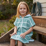Young girl wearing Amalfi teal and white striped kids hooded towel, on the back steps at home