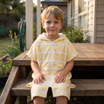 Young boy in the Amalfi yellow and white kids zip hooded towel, on the back steps at home