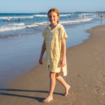 Girl in the Amalfi yellow and white kids zip hooded towel, walking on the beach