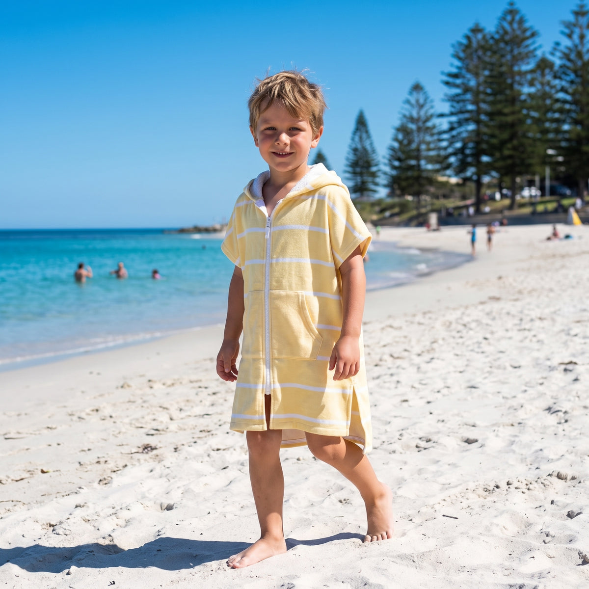 Amalfi kids hooded towel in yellow and white stripes worn by a young boy, on Cottesloe Beach, Perth