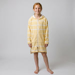 Girl in the long sleeve Amalfi yellow and white striped kids hooded towel, studio front view