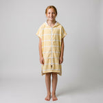 Amalfi kids hooded towel in yellow and white stripes worn by a girl, studio photo, front view