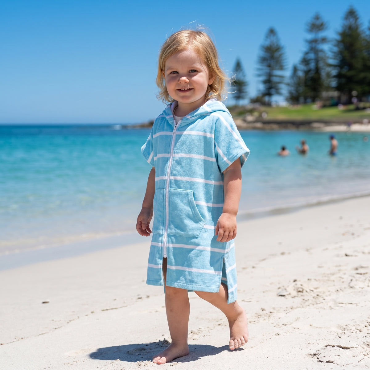 Toddler girl wearing Amalfi aqua and white striped toddler hooded towel, on Cottesloe Beach, Perth