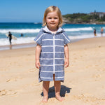 Toddler girl wearing Amalfi navy and white striped toddler hooded towel, on Bondi Beach, Sydney
