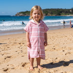Amalfi toddler hooded towel in pink and white stripes worn by a toddler girl, on Bondi Beach, Sydney