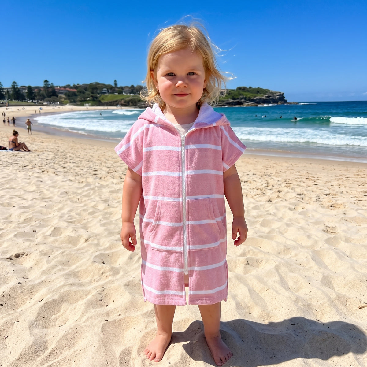 Amalfi toddler hooded towel in pink and white stripes worn by a toddler girl, on Bondi Beach, Sydney