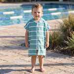 Toddler boy in the Amalfi teal and white toddler zip hooded towel, beside an outdoor pool
