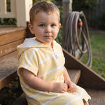 Toddler boy in the Amalfi yellow and white toddler zip hooded towel, on the back steps at home