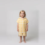 Amalfi toddler hooded towel in yellow and white stripes worn by a toddler girl, studio photo, front view