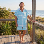 Man wearing the Amalfi Aqua White Turkish hooded towel on a timber deck after swimming
