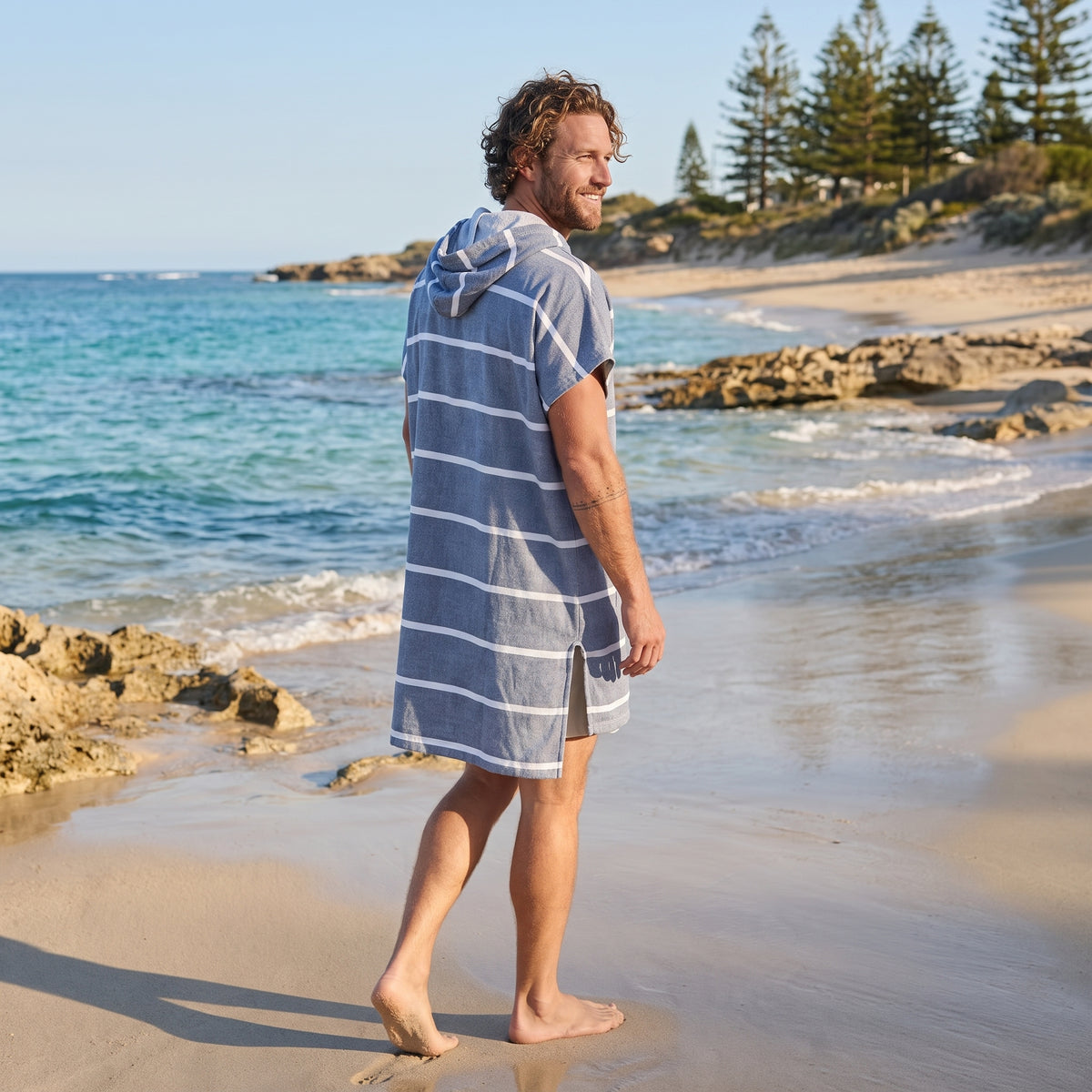 Man wearing the Amalfi Navy White Turkish hooded towel while walking along a Western Australian beach