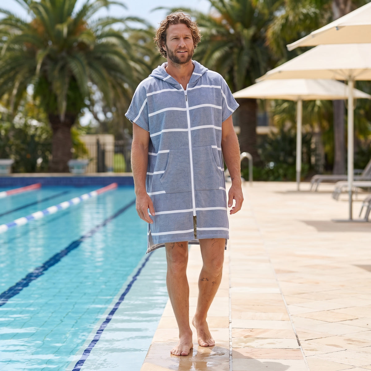 Man wearing the Amalfi Navy White Turkish hooded towel beside an outdoor swimming pool
