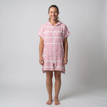 Woman wearing the Amalfi Pink White Turkish hooded towel, front view on a plain studio background