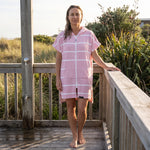 Woman wearing the Amalfi Pink White Turkish hooded towel on a timber deck after swimming