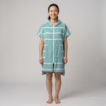Woman wearing the Amalfi Teal White Turkish hooded towel, front view on a plain studio background