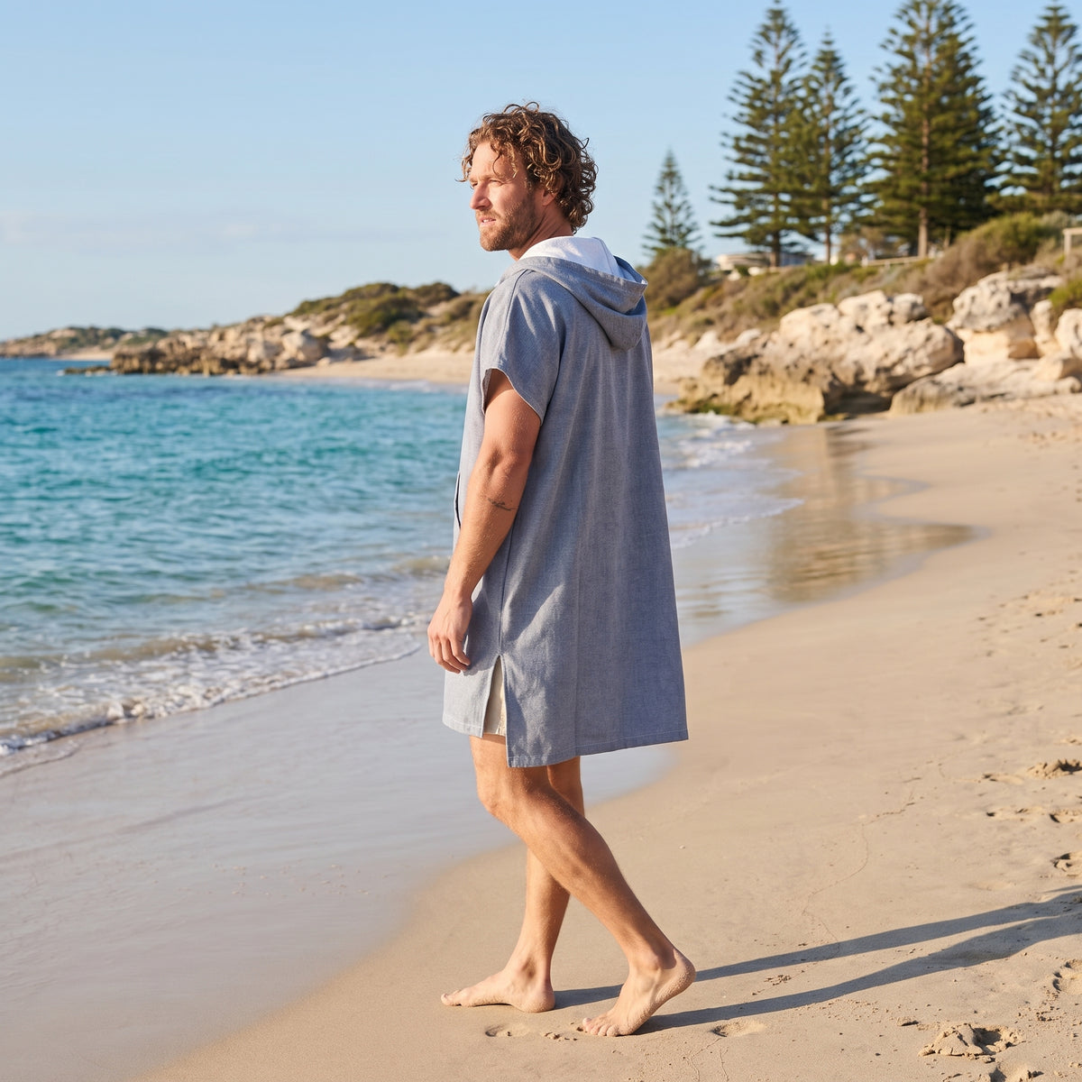 Man wearing the Santorini Navy Turkish hooded towel while walking along a Western Australian beach