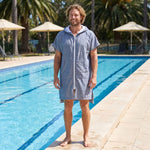 Man wearing the Santorini Navy Turkish hooded towel beside an outdoor swimming pool