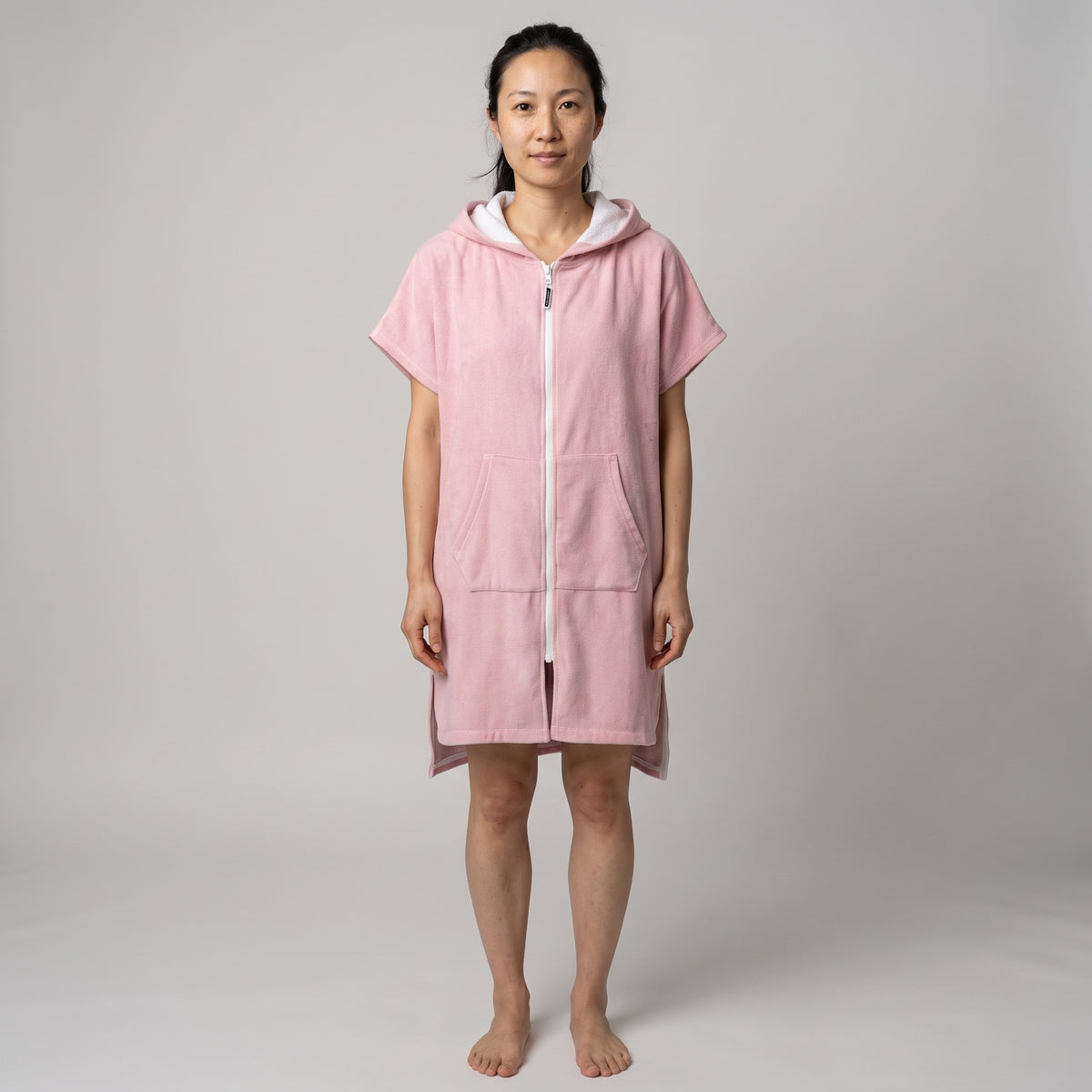 Woman wearing the Santorini Pink Turkish hooded towel, front view on a plain studio background