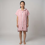 Woman wearing the Santorini Pink Turkish hooded towel, front view on a plain studio background