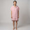 Woman wearing the Santorini Pink Turkish hooded towel, front view on a plain studio background