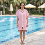 Woman wearing the Santorini Pink Turkish hooded towel beside an outdoor swimming pool