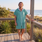 Man wearing the Santorini Teal hooded towel on a timber deck after swimming